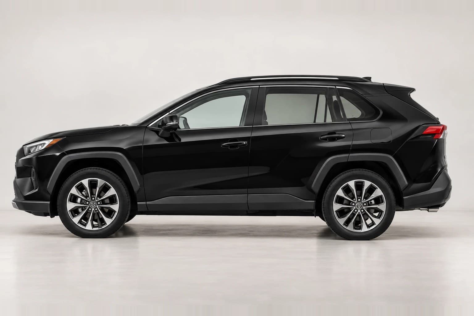 Black Toyota RAV4 SUV in side profile on a neutral studio background